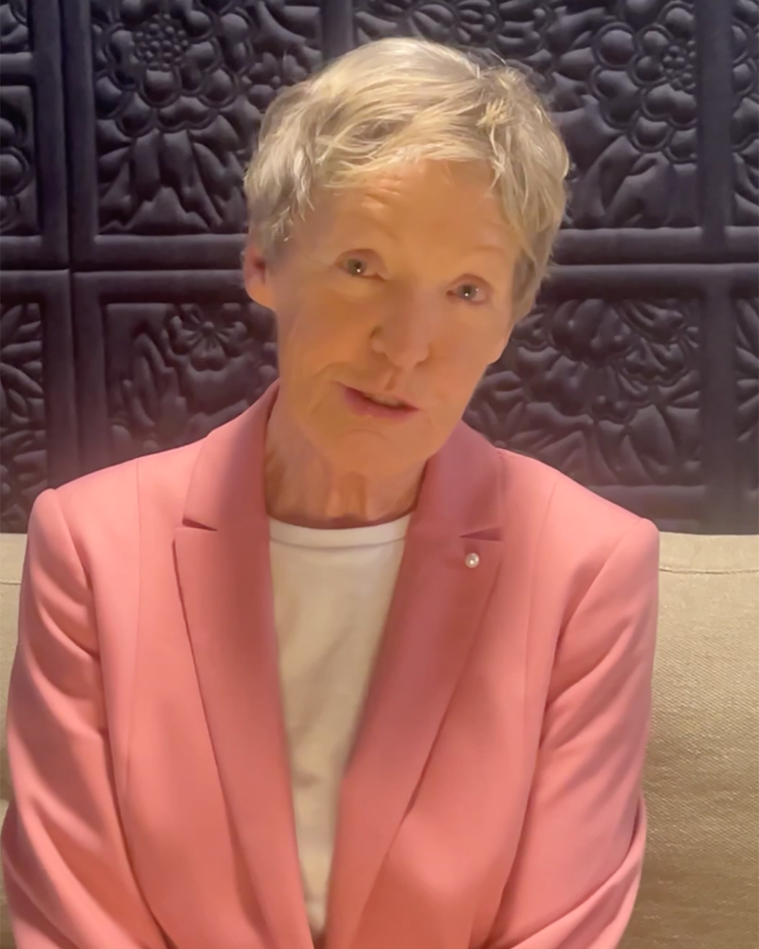 Geschäftsführerin im Interview, freundlich in die Kamera blickend vor dekorativer Wand.